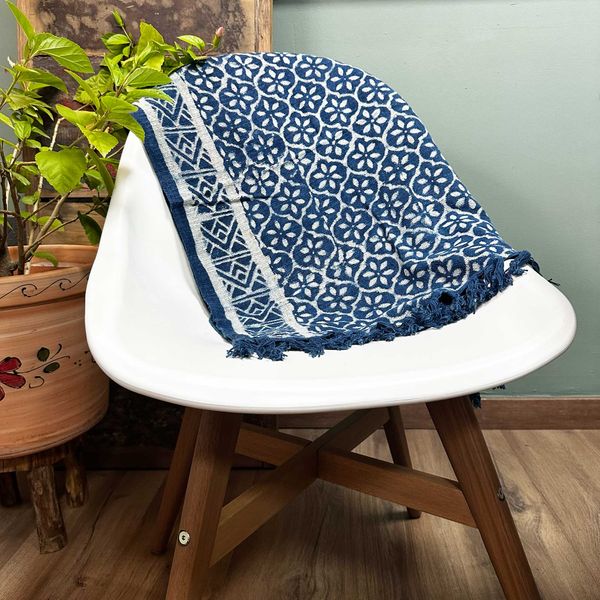 Petit jeté indigo 170 x 60 cm à motif floral dense bordé de rayures, posé sur le dossier d'une chaise blanche