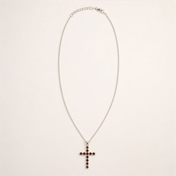 Pendentif croix en métal argenté serti de petits grenats rouge sombre, sur chaîne fine