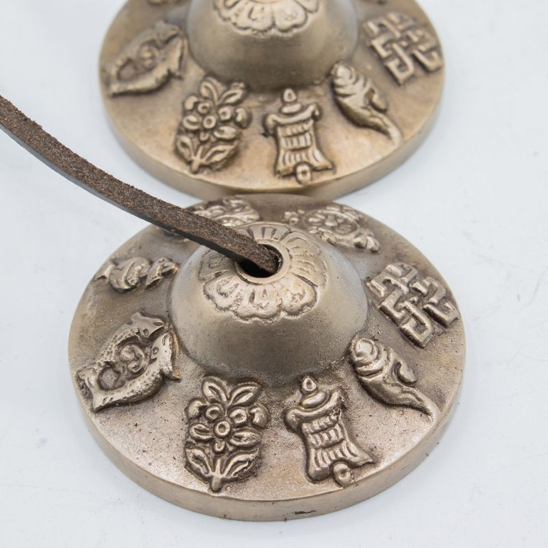 Cymbales tingsha reliées par leur cordon de cuir