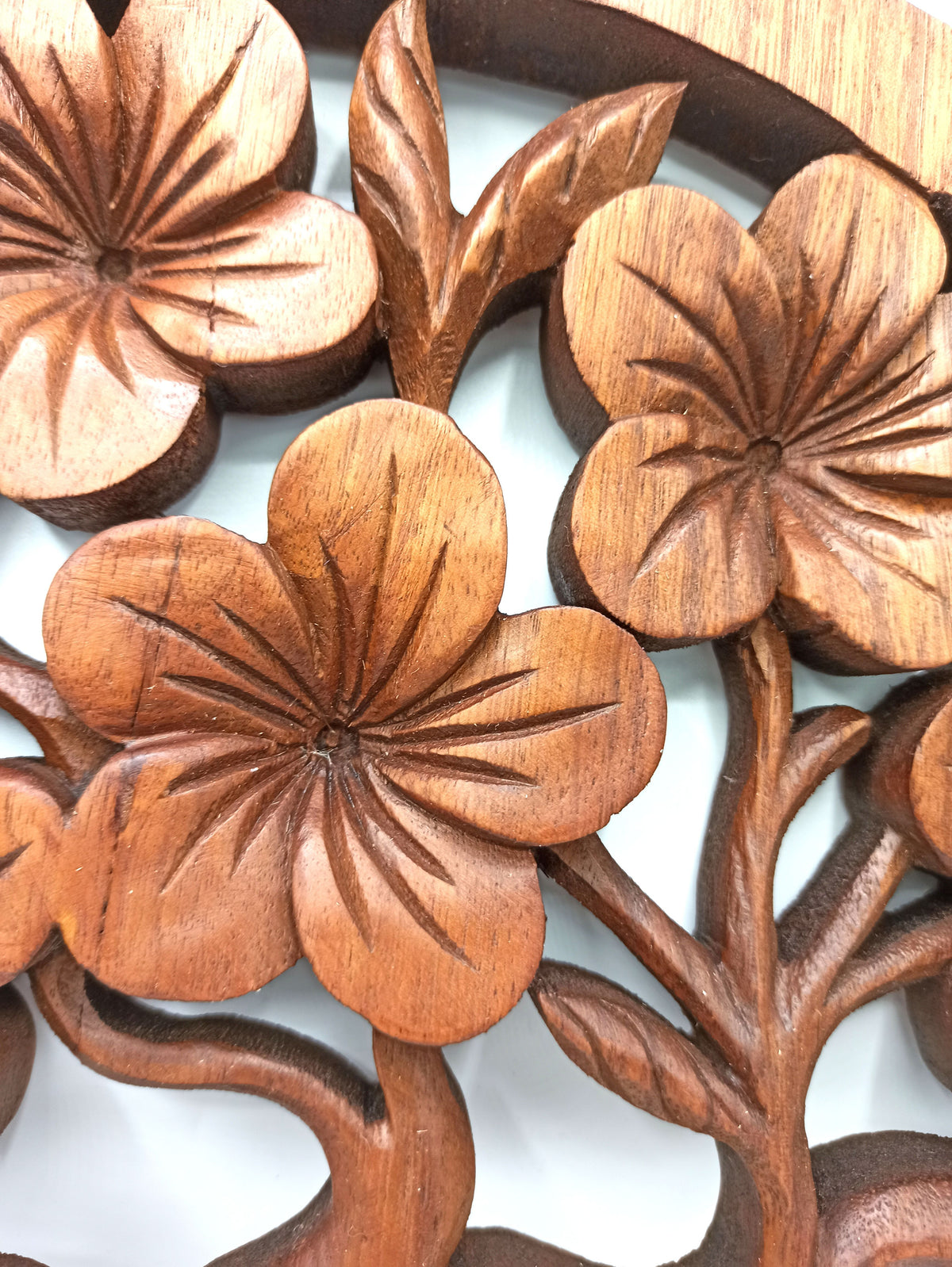 Détail des fleurs de frangipanier à cinq pétales creusées une à une dans le bois