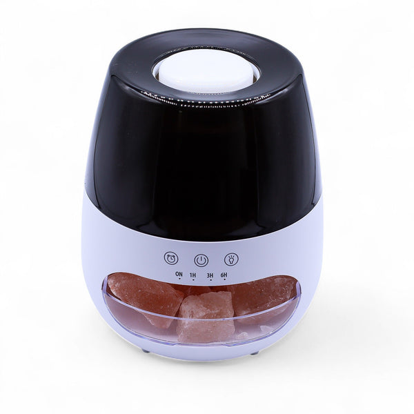 Diffuseur blanc à dôme noir laqué, avec un tiroir transparent rempli de pierres de sel rose à l'avant et des touches tactiles ON 1H 3H 6H
