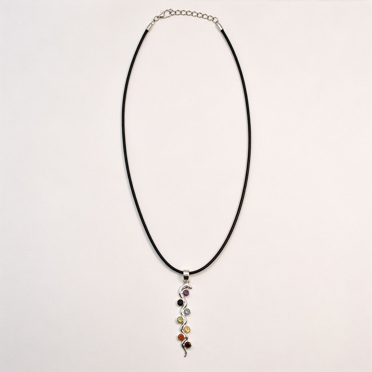Pendentif serpent en métal argenté ponctué de sept petites pierres de couleur, sur cordon noir