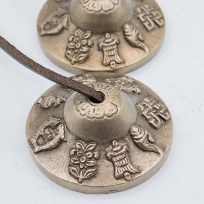 Cymbales tingsha reliées par leur cordon de cuir