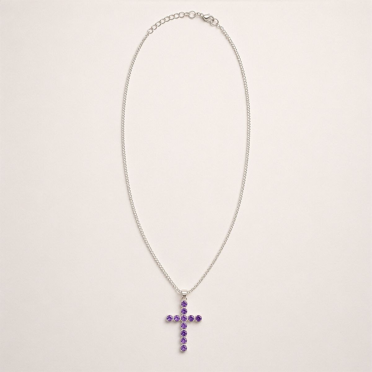 Pendentif croix en métal argenté serti de petites améthystes violettes, sur chaîne fine